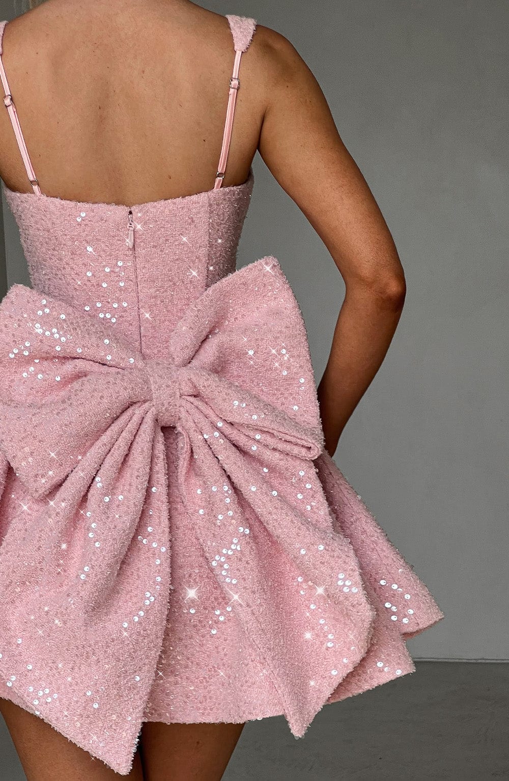 Model wearing a stunning pink sequin backless mini dress with a bow, perfect for a glamorous party.