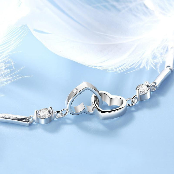 Close-up of a women's double heart link bracelet, shimmering silver and crystal detail, a beautiful accessory.