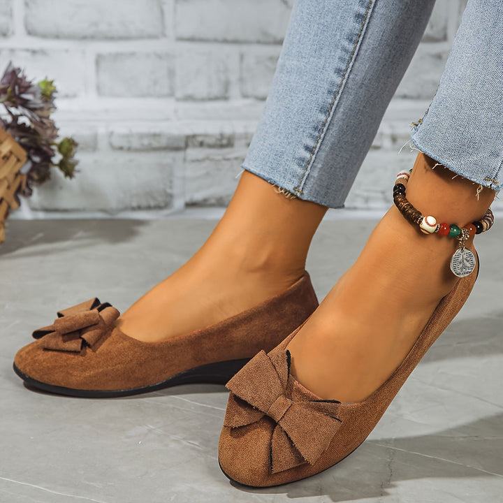 Close-up of the elegant bow detail on women's comfortable slip-on wedge heels. Stylish footwear.