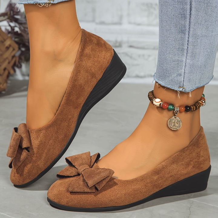 Pair of elegant women's slip-on wedge shoes with lovely bow detail. Comfortable & versatile ladies footwear.