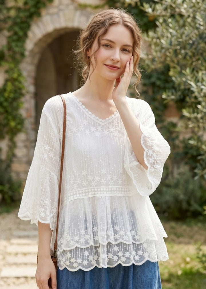 Women's embroidered blouse with elegant floral details, tiered lace hem, and half sleeves for summer fashion.