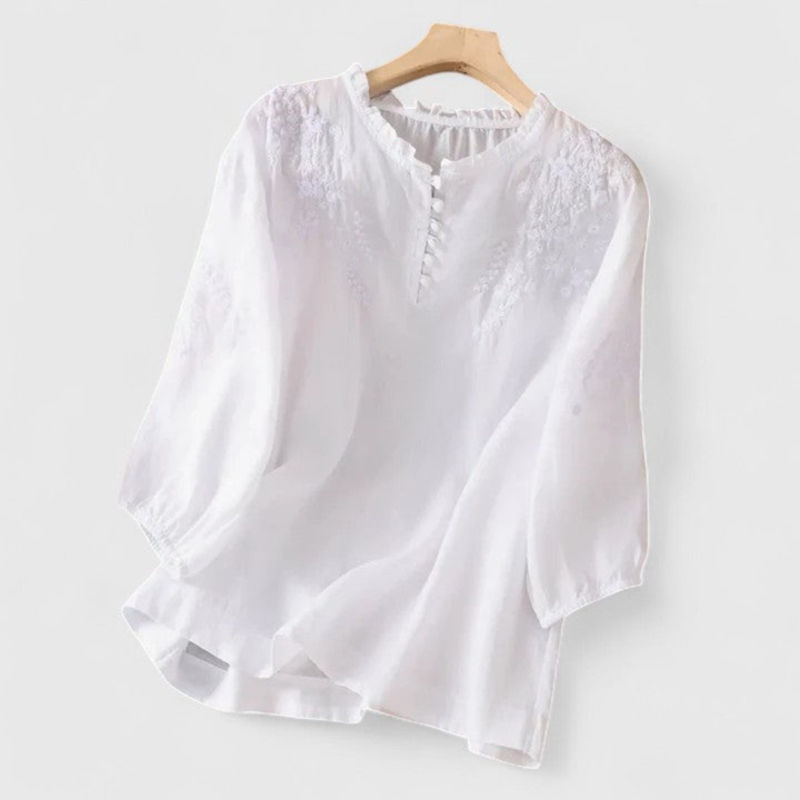 Women's embroidered white blouse with a stylish ruffle collar & playful pom-poms, perfect for a chic summer look.