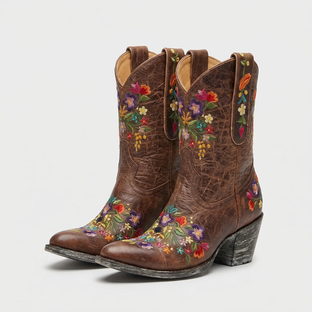Close-up of vibrant floral embroidery on a women's western ankle boot, highlighting unique design details.