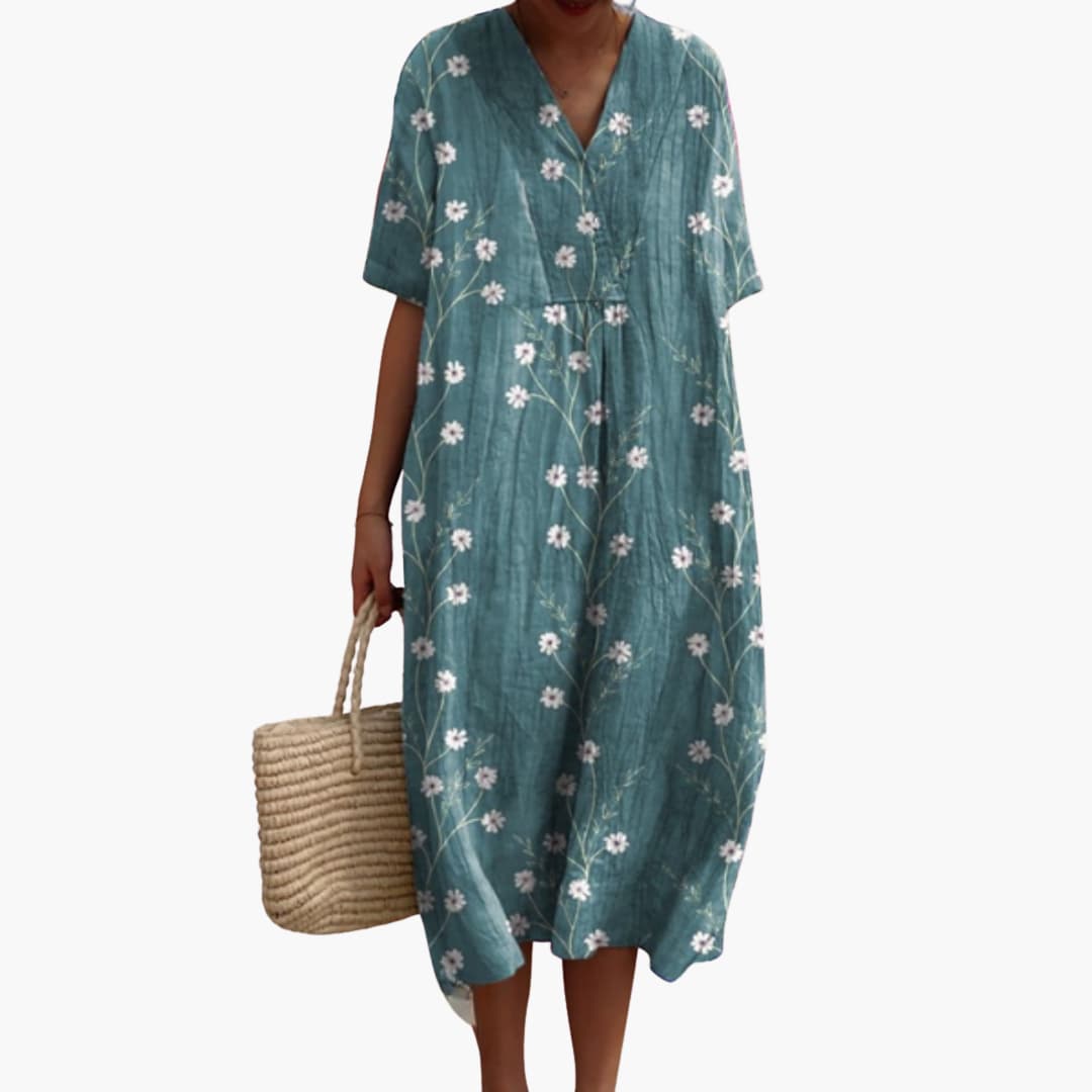 Woman wearing a flowy floral V-neck midi dress, short sleeve, oversized, ideal for casual summer outings.