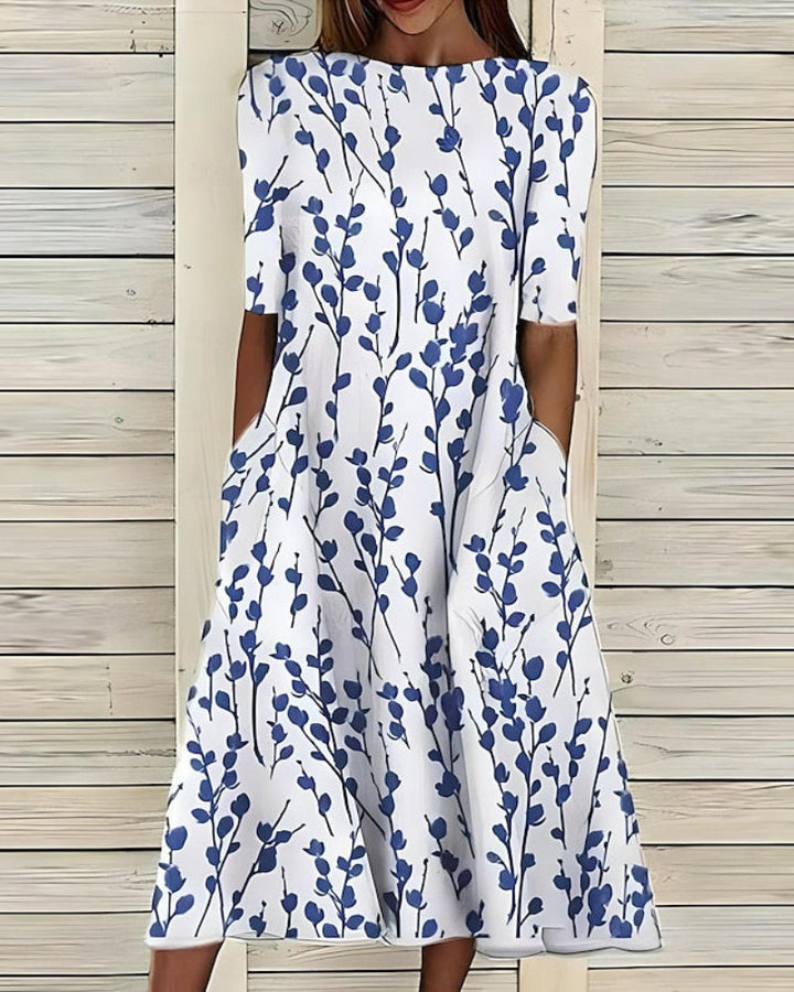Women's flowy A-line midi dress with botanical print, pockets, crew neck, and short sleeves for summer fashion.