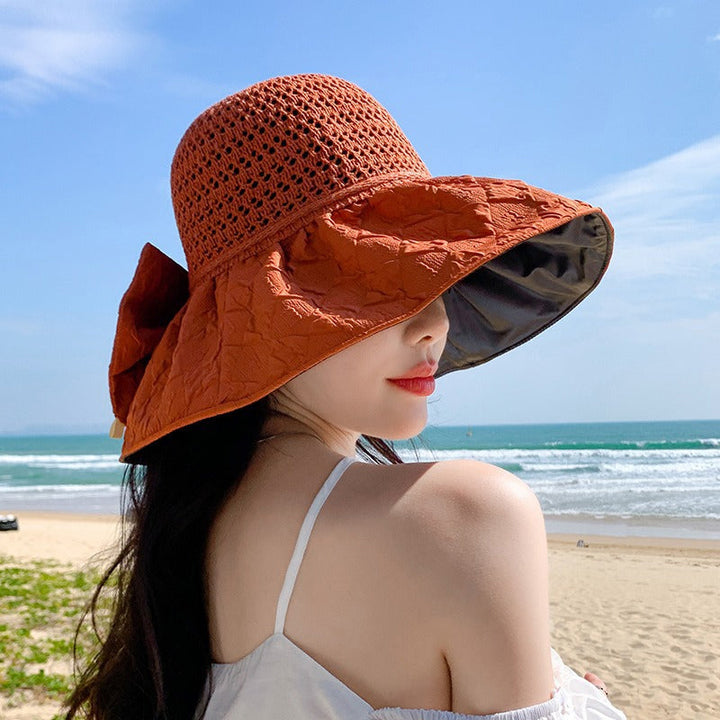 Elegant women's foldable wide-brim sun hat with a bow, perfect for a sophisticated beach look.