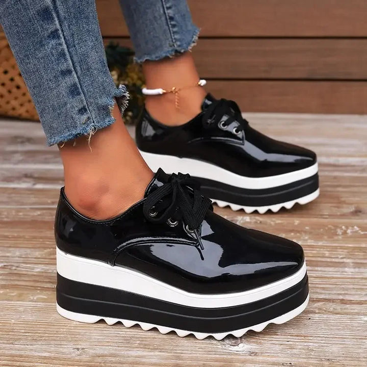 A woman tying the laces of her glossy platform sneakers, showcasing the product in use, comfort focus.