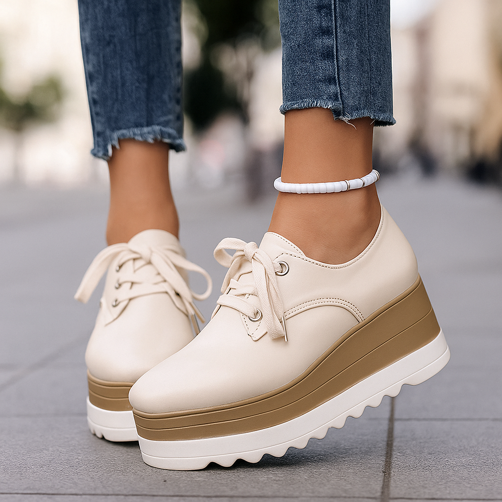 Women's platform sneakers in a glossy material, worn on foot, demonstrating casual and chic style.