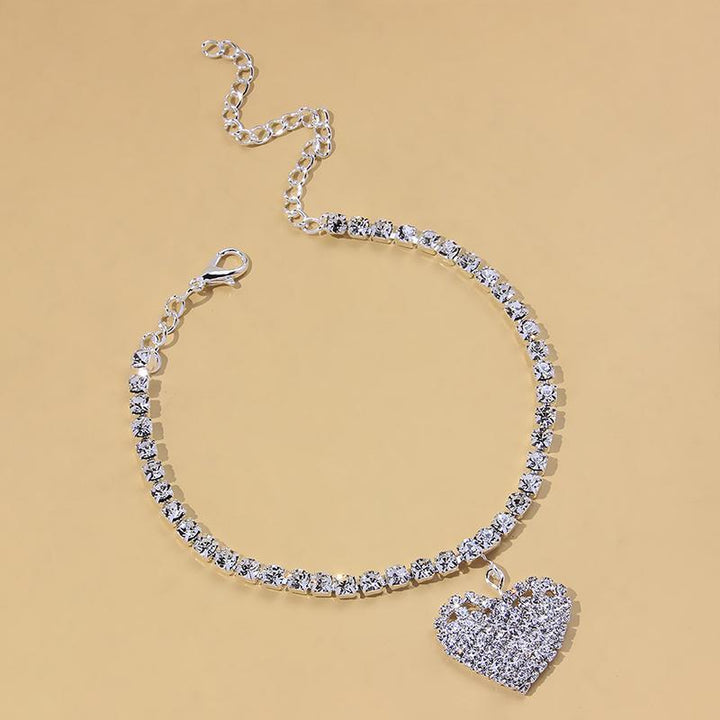 Delicate women's anklet with a shimmering rhinestone heart charm, golden finish, summer jewelry.