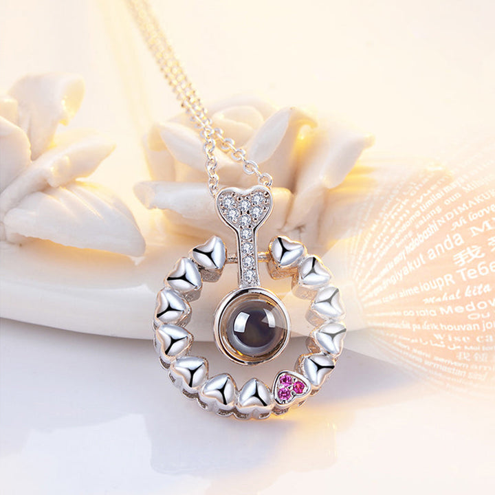 Close-up of the delicate chain connected to the rose gold 'I Love You' projection necklace.