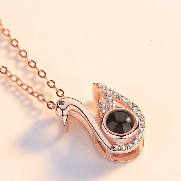 Close-up of rose gold '100 Languages I Love You' projection pendant, intricate design, women's jewelry.