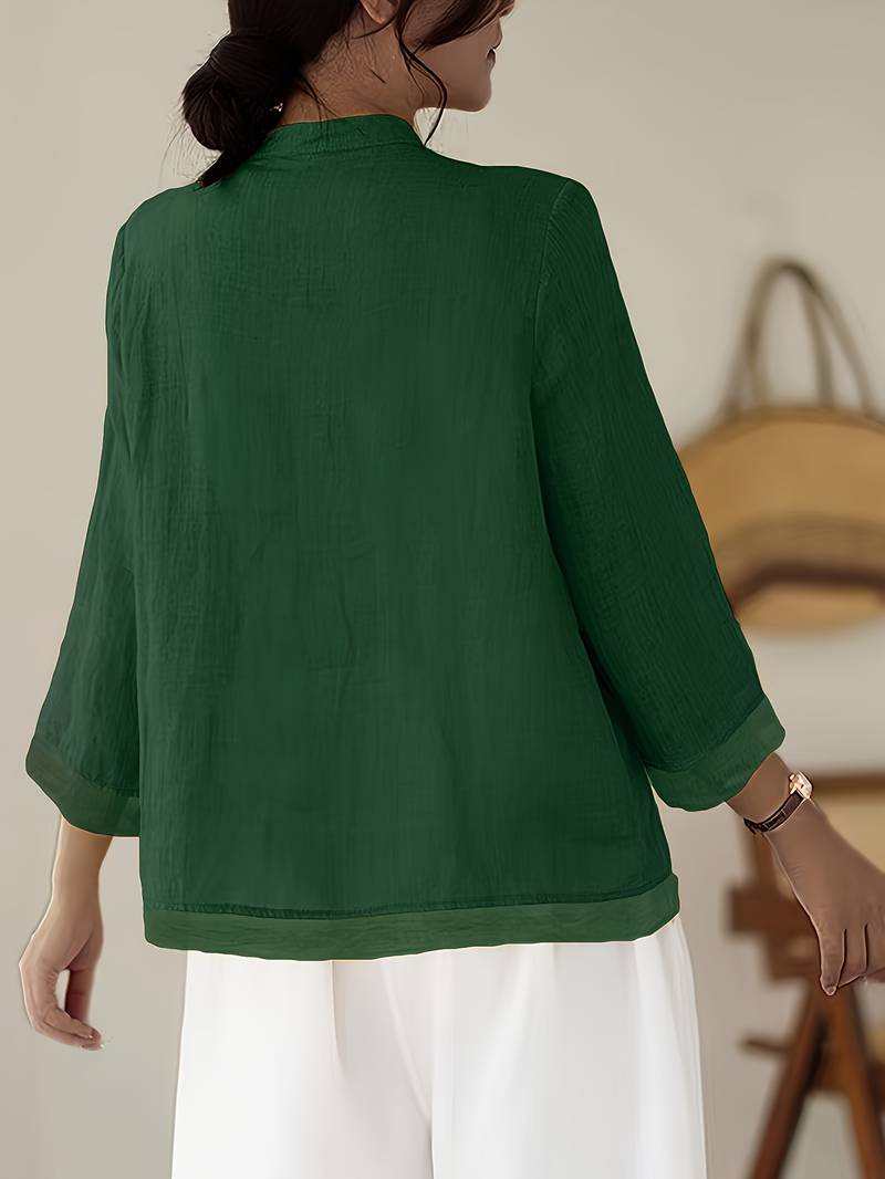 Close-up: Mandarin collar & decorative frog buttons on a women's tailored blouse.