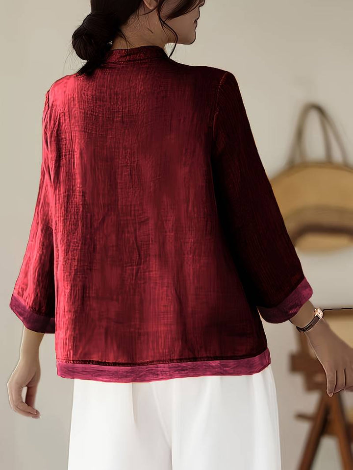 Woman modeling a casual elegant mandarin collar blouse with frog buttons, office wear.