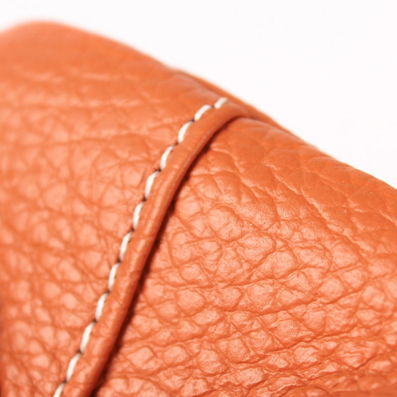 Hand holding a compact red leather coin purse, demonstrating its small size