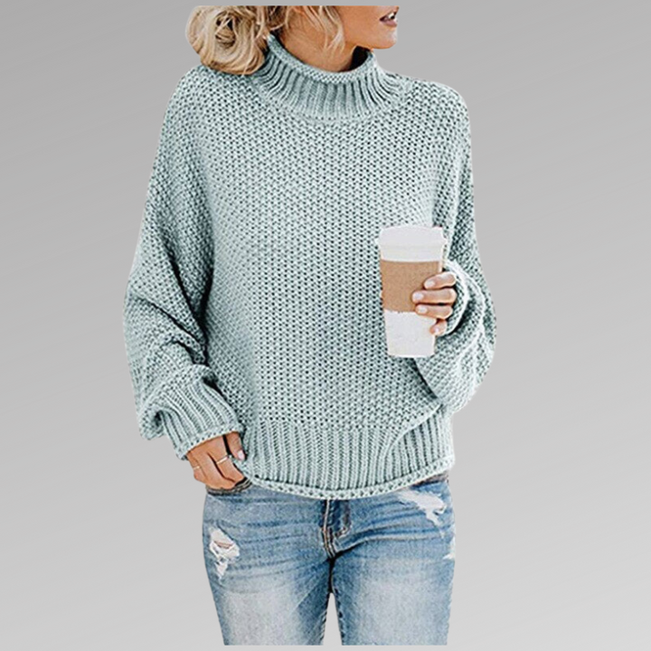 Back view of a women's oversized chunky knit turtleneck sweater, showcasing its warm, relaxed fit.