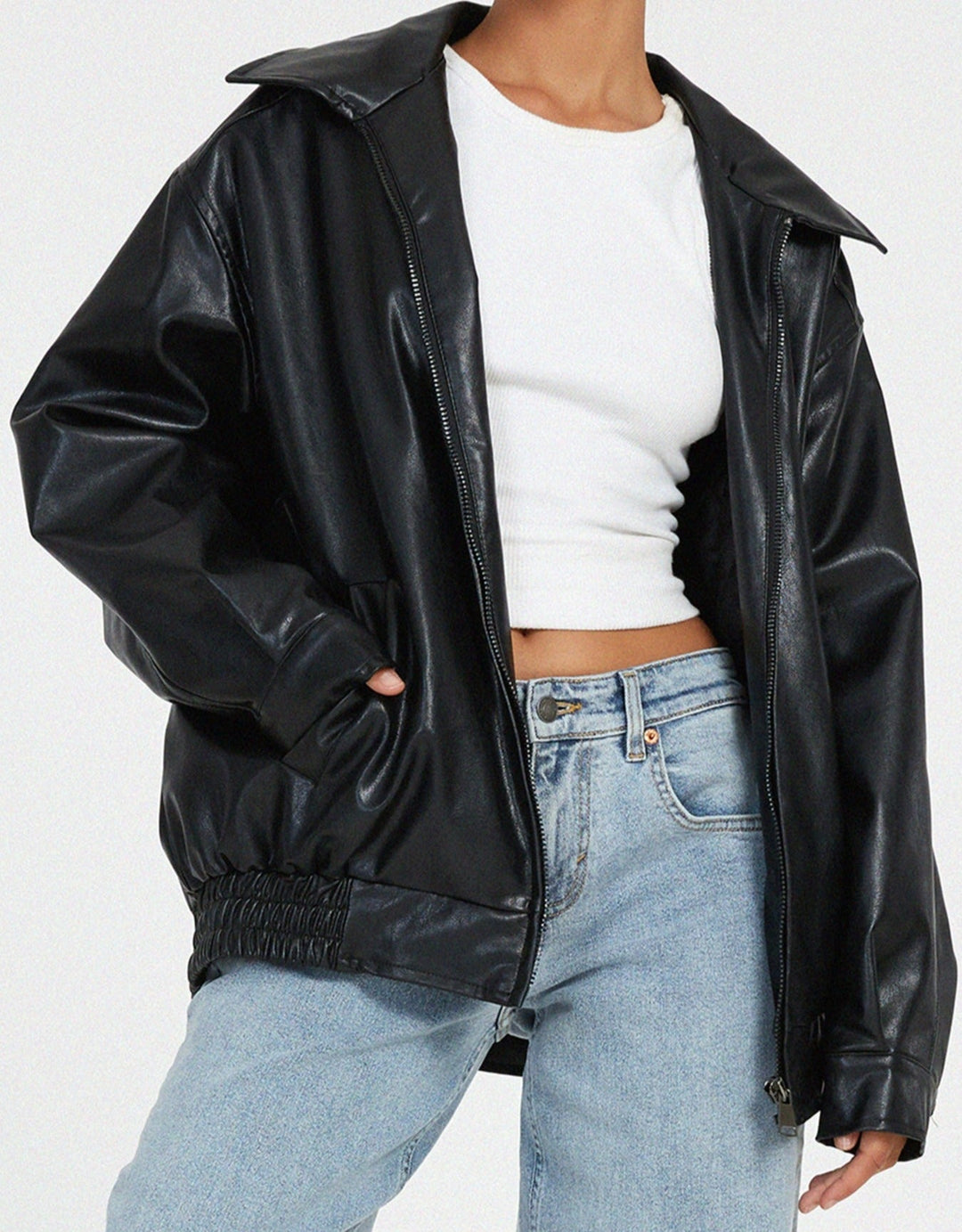 Side profile of a woman in an oversized black faux leather bomber jacket, chic and comfortable outerwear.
