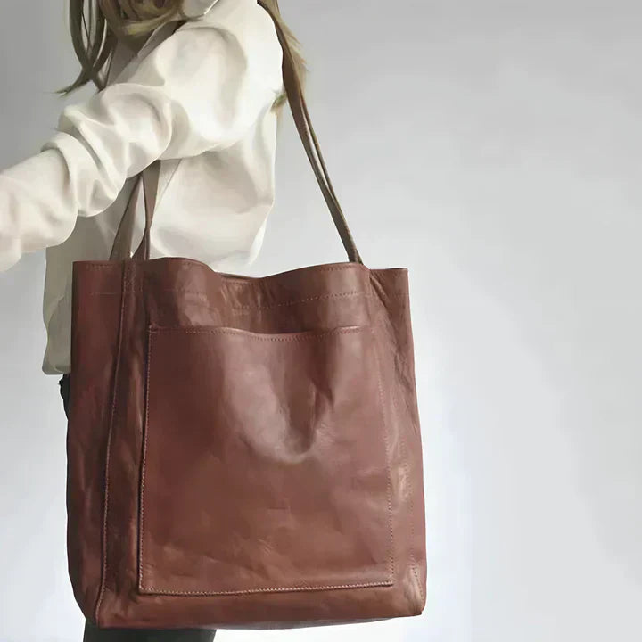 Women's oversized grain leather tote bag with large external pocket, perfect for everyday use.