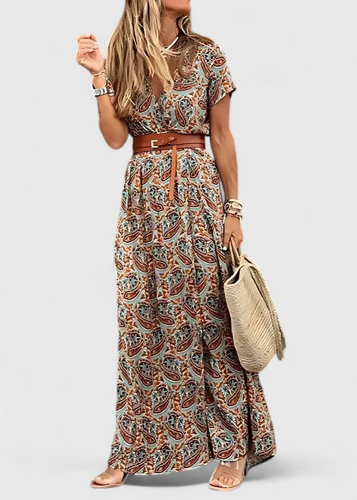 Woman wearing a flowy paisley print V-neck maxi dress with a belted waist and high side slit, boho style.