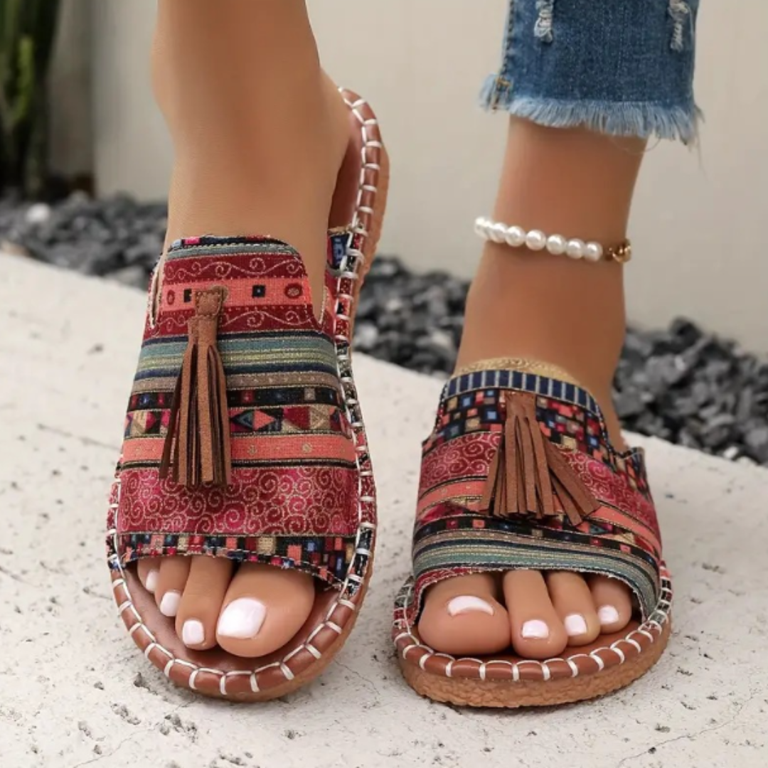 Women's patterned open toe slide sandals with tassels. Comfortable flat sole summer casual footwear.