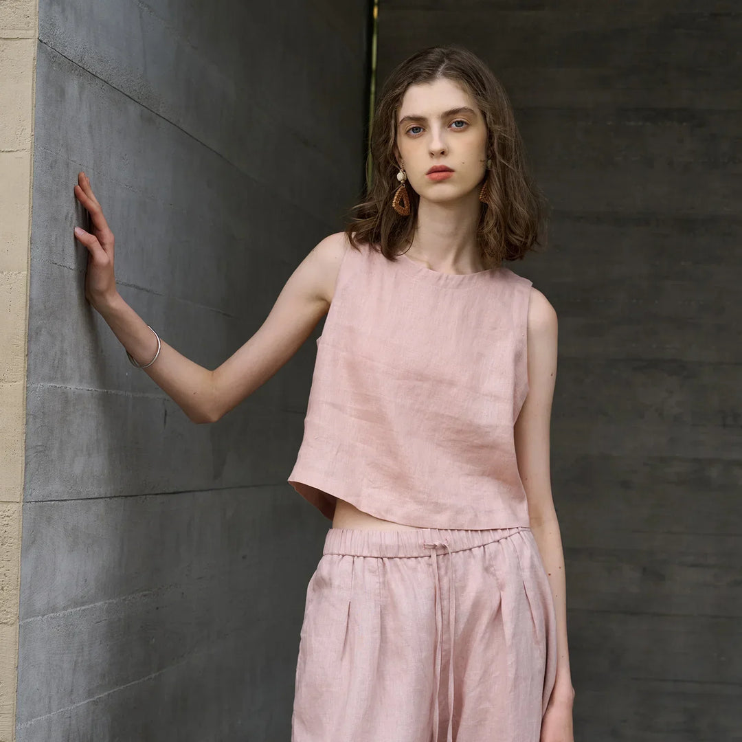 Women's pink asymmetric sleeveless crop top with crew neck, perfect for stylish summer fashion.