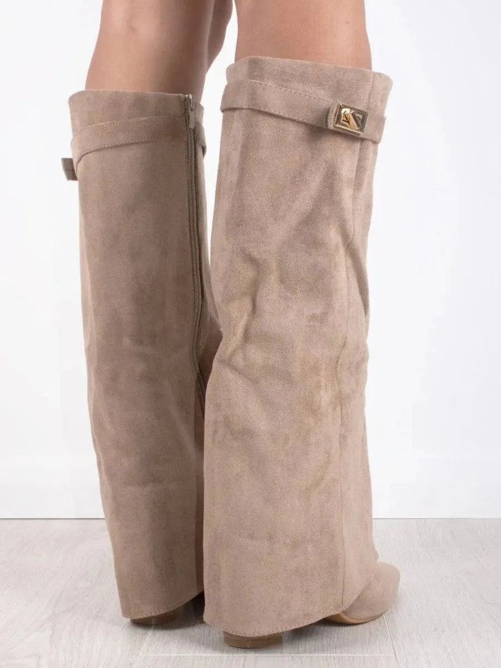 Woman wearing black pointed wedge knee-high boots, styled with a fall outfit, elegant.
