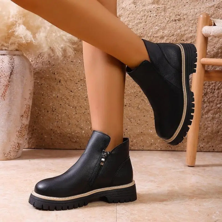 Side profile of women's leather ankle boots, showcasing the sturdy lug sole and elegant design.