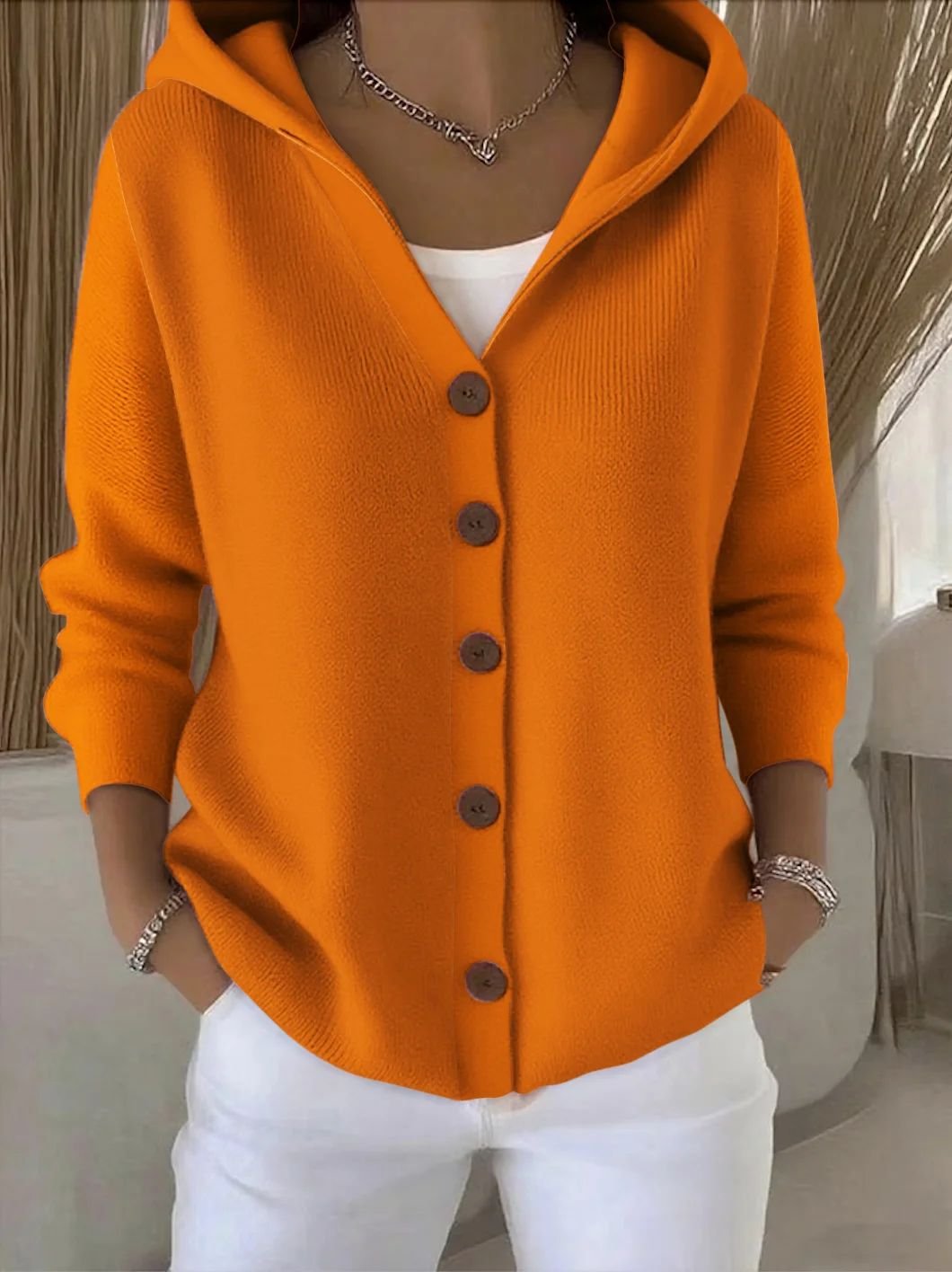 Close-up of women's relaxed fit hooded knit cardigan, showcasing button front detail & soft texture.