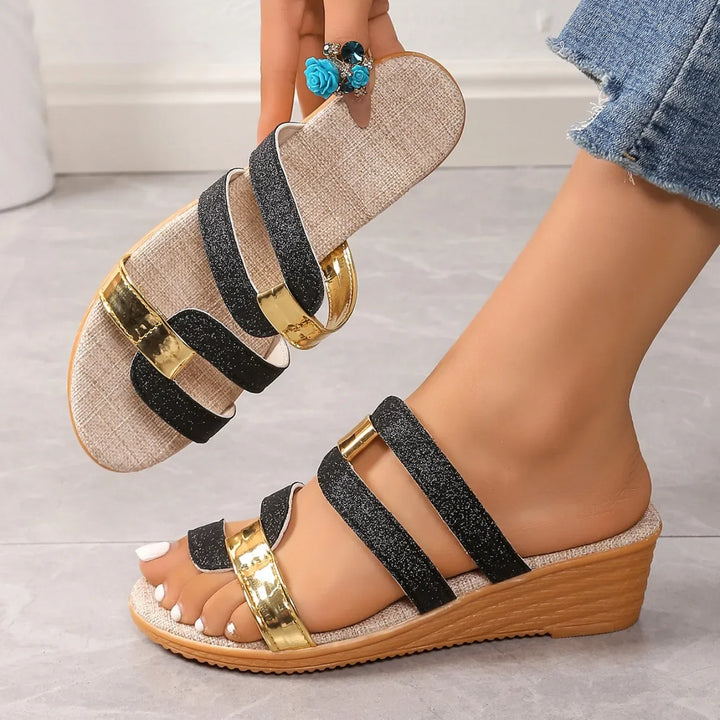 Close-up of women's metallic triple-strap sandals, showing shimmery material and elegant design.