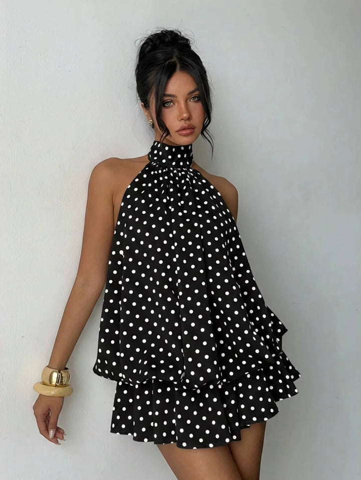 Women modeling a sleeveless halter mini dress, twirling to highlight the flirty ruffle hem and open back detail.