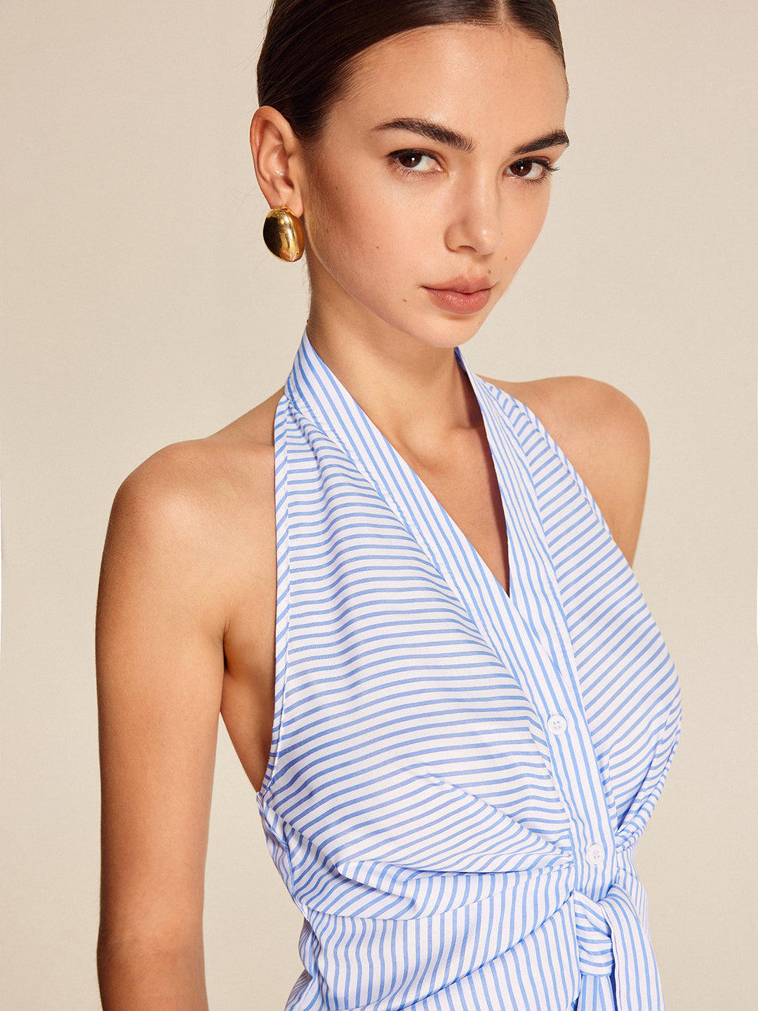 Stylish women's striped halter blouse with a tie-front detail, offering an elegant look for work or summer events.