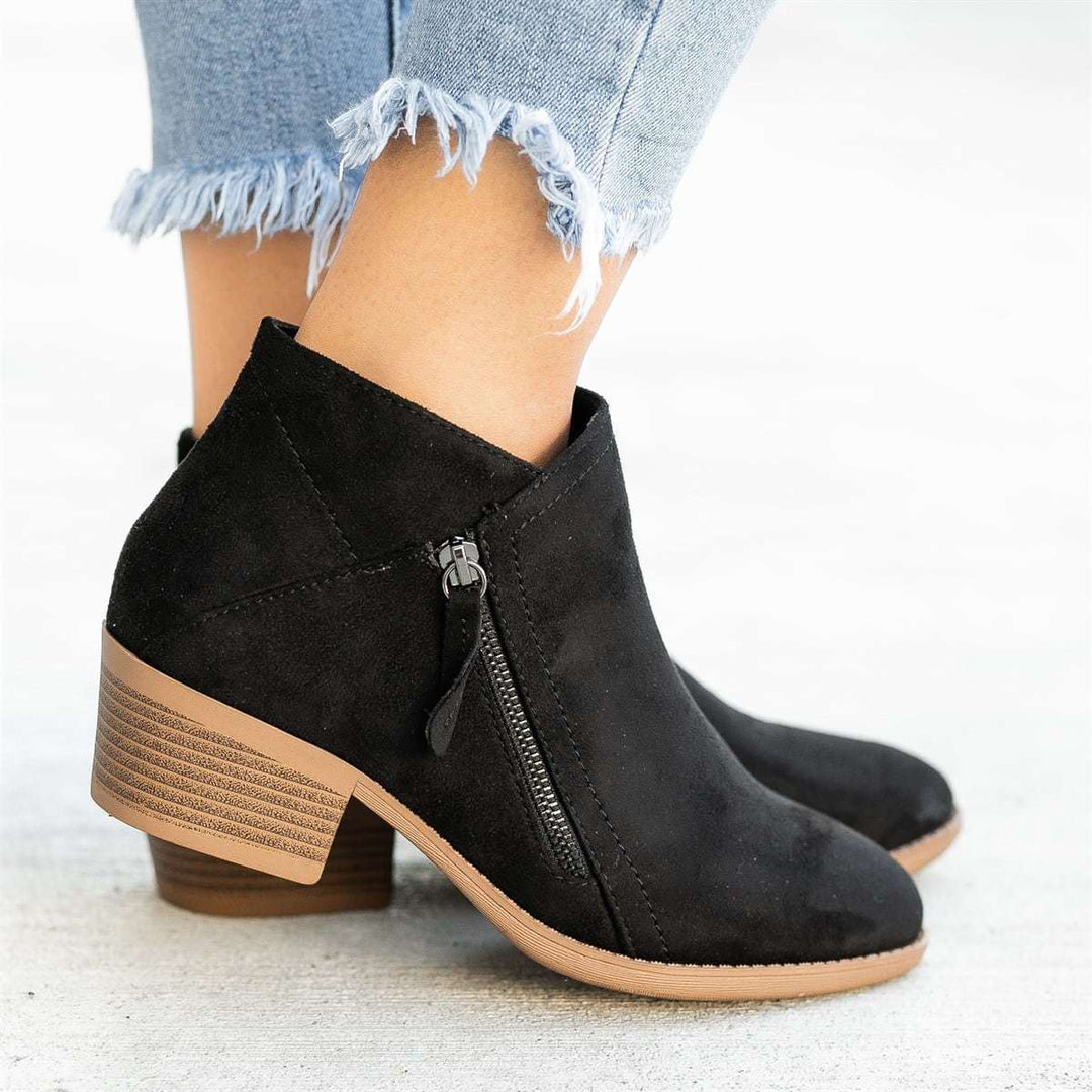 Model wearing women's fashionable black zip-up ankle boots, versatile casual footwear