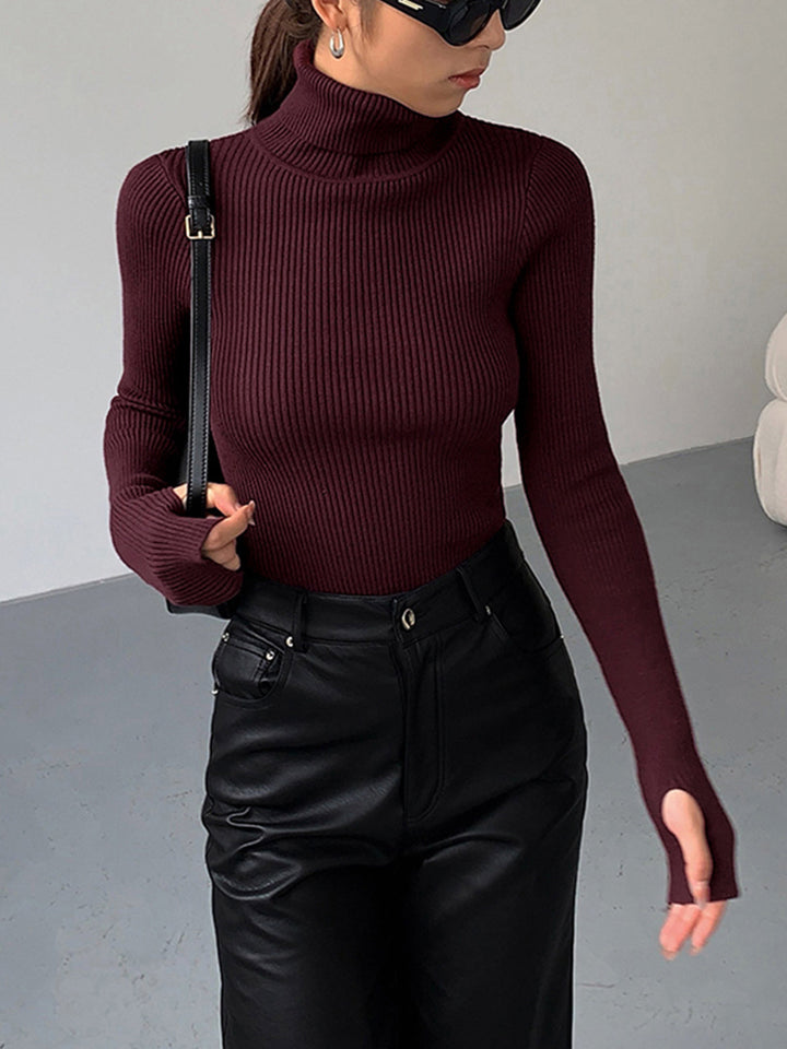 Model wearing a form-fitting black ribbed turtleneck sweater, highlighting its flattering silhouette.