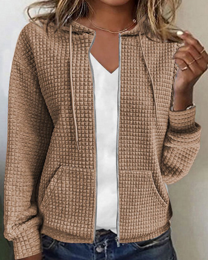 Cozy women's textured zip-up hoodie with front pockets & an adjustable hood, offering stylish everyday comfort.