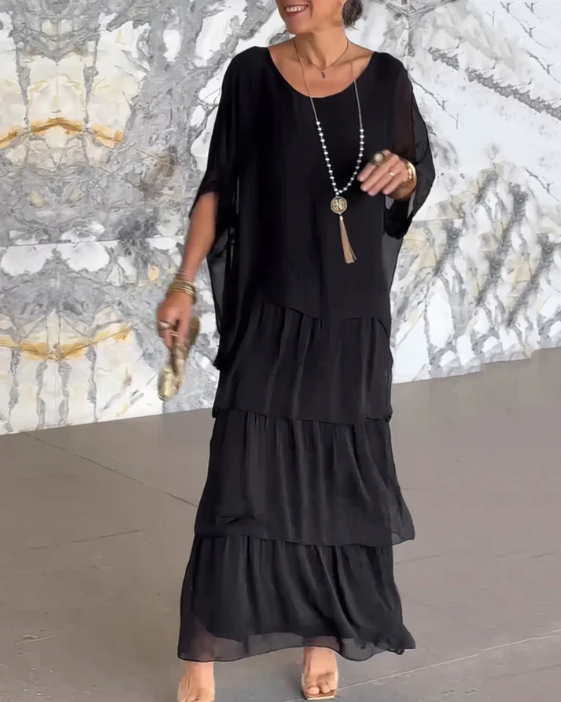 Back view of a women's flowy tiered maxi dress with long sleeves, emphasizing its elegant, relaxed drape.