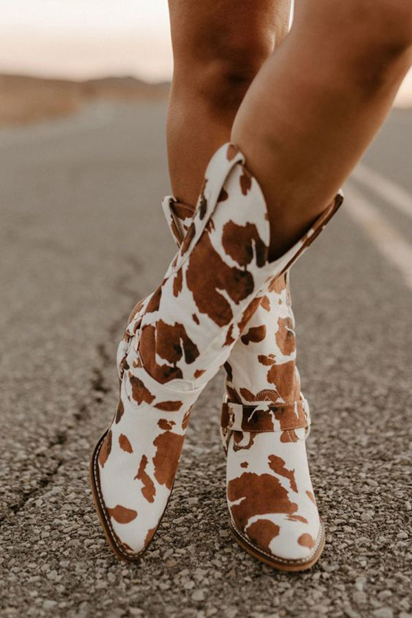 Fashionable women's cow print boots featuring a mid-heel and decorative belt, showcasing trendy western style.