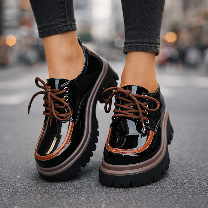 Close-up of women's gray platform sneakers, showing lug sole texture & detailed lace-up closure