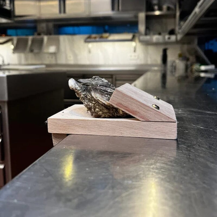 Chef using a wooden oyster shucking clamp to prepare seafood, kitchen gadget