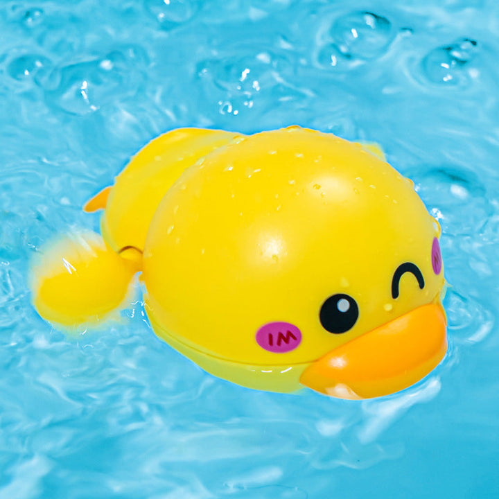 Overhead view of a wind-up duck bath toy in a child's hand, highlighting its smooth design